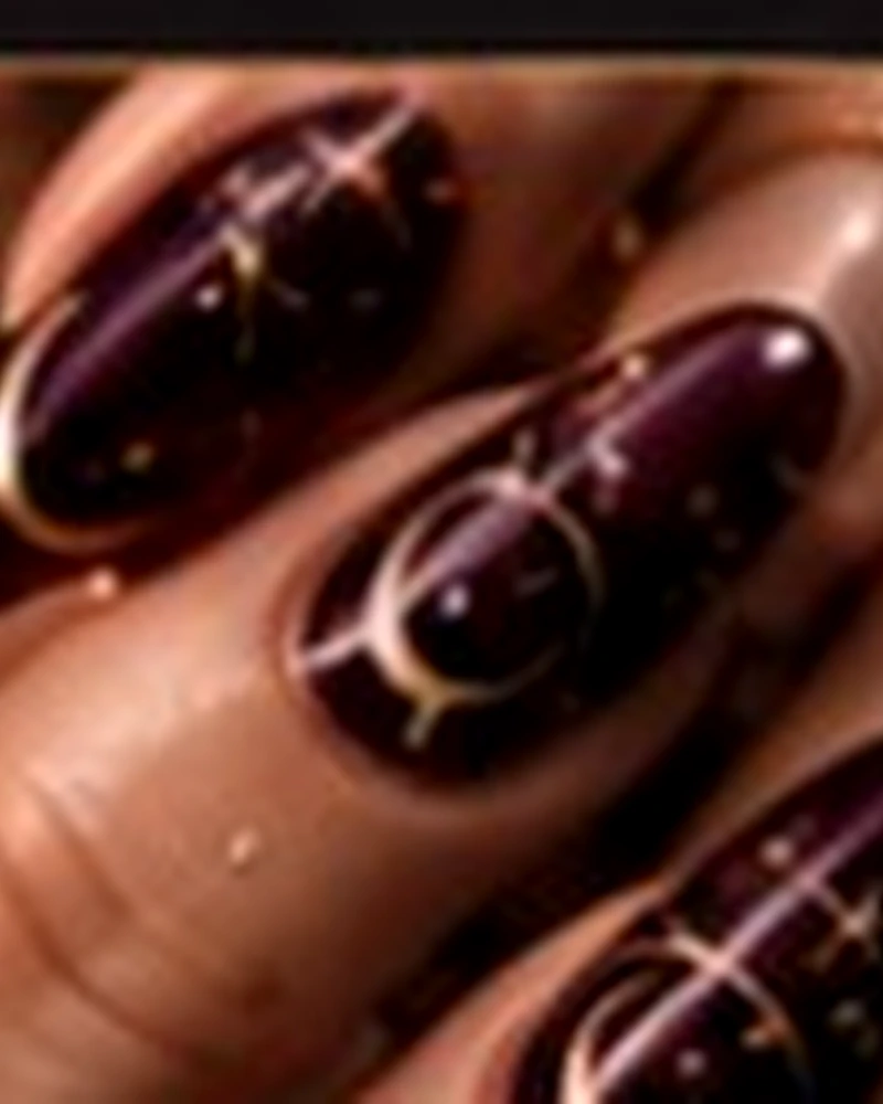 Nail art nera e bordeaux con lune e stelle dorate