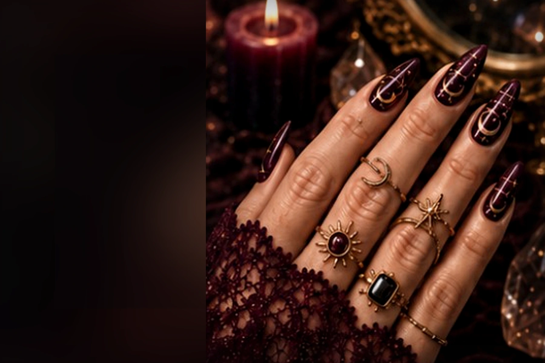 Mano con manicure nera e bordeaux, gioielli dorati, candela e cristalli
